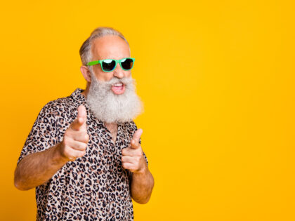Portrait of funky old bearded man in eyeglasses eyewear feel cool crazy point at you wearing leopard shirt isolated over yellow background
