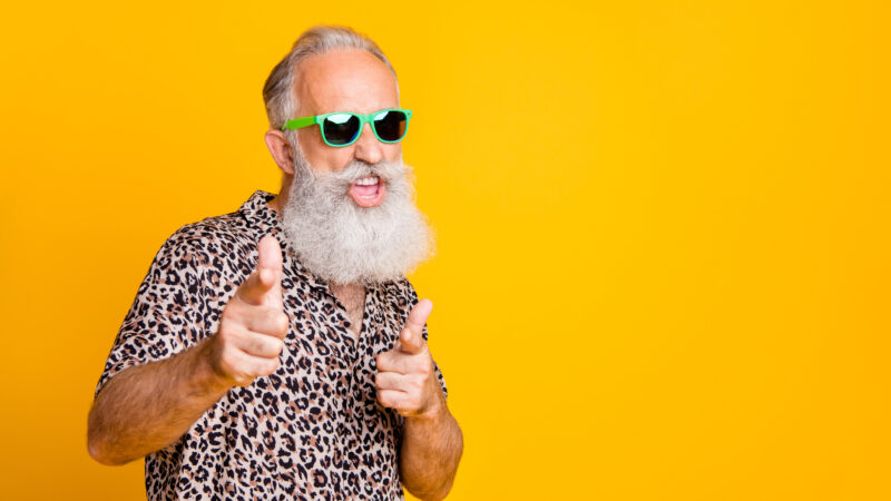 Portrait of funky old bearded man in eyeglasses eyewear feel cool crazy point at you wearing leopard shirt isolated over yellow background