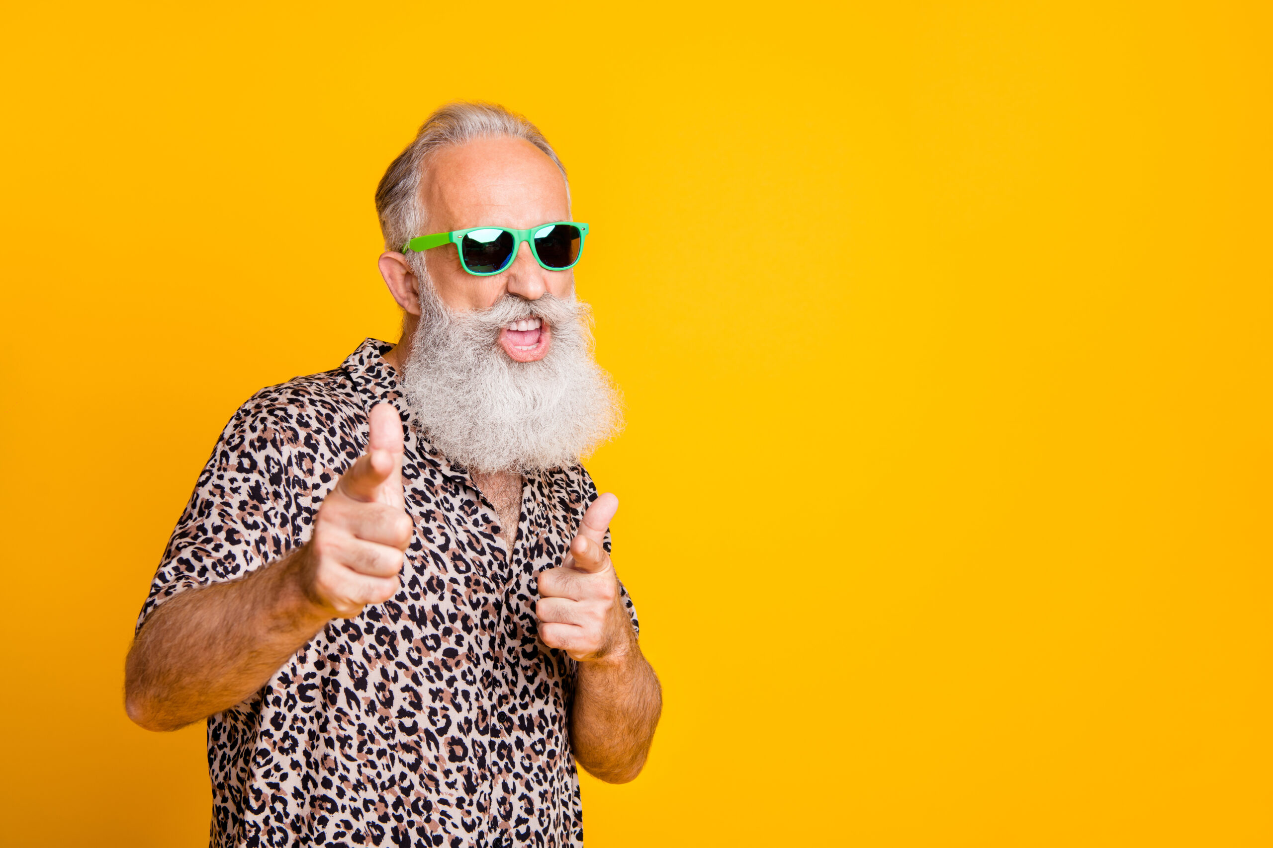 Portrait of funky old bearded man in eyeglasses eyewear feel cool crazy point at you wearing leopard shirt isolated over yellow background